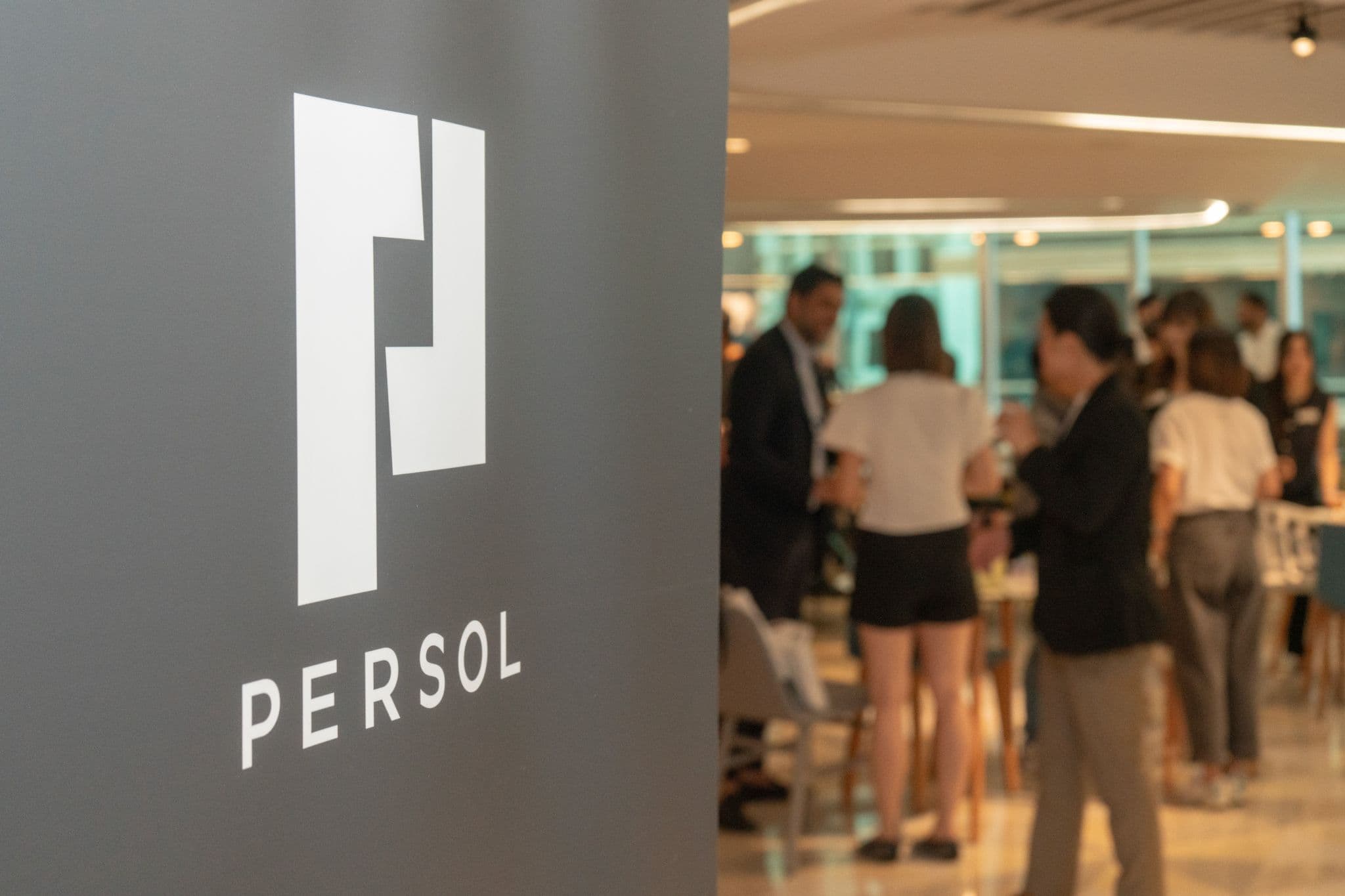 PERSOL event branding in the foreground with guests networking
